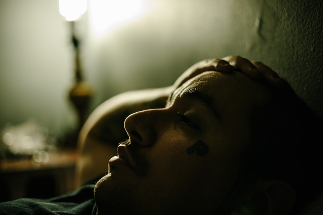 A person awake at night near a window, representing disrupted sleep from frequent urination